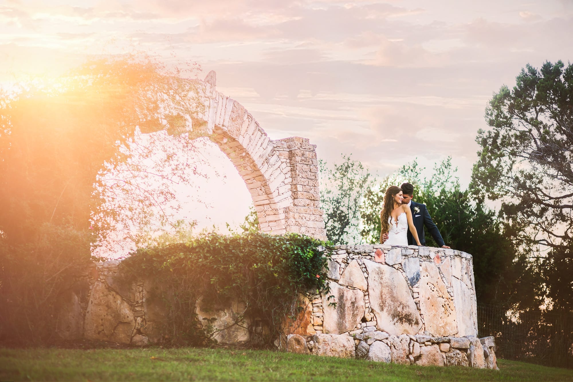 Bride and groom flirt while on edge of hill country view