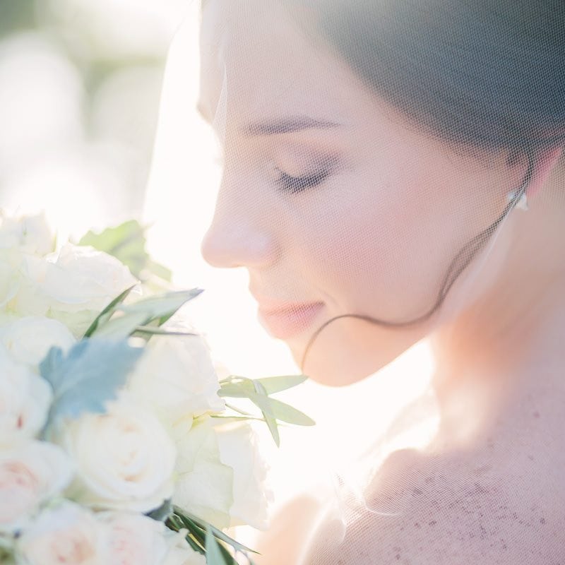 Bride looks at her flowers as sunlight backlights her
