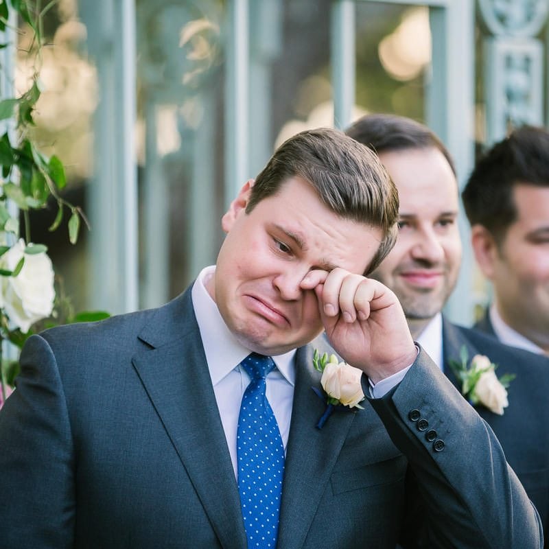 groom wipes tear from his eye as his bride walks down the aisle