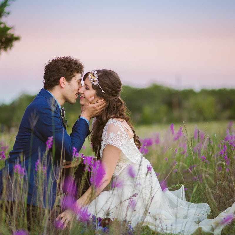 bride and groom kiss in a field of bluebonnets at sunset