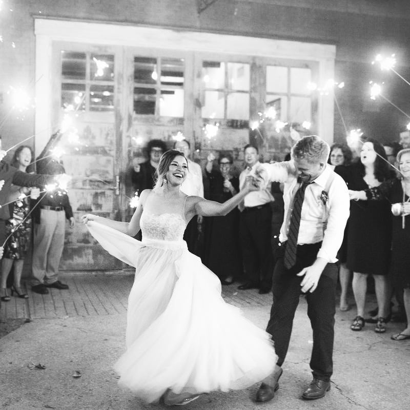 groom twirls his bride as they exit reception surrounded by guests holding sparklers