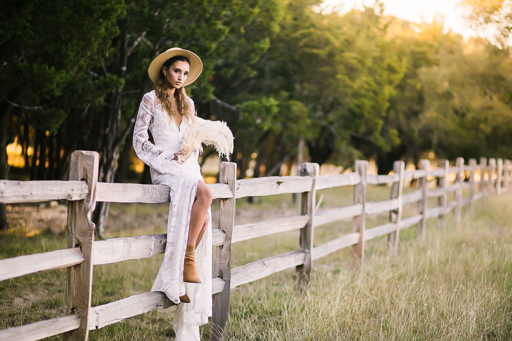 Woman in hat sits on fence
