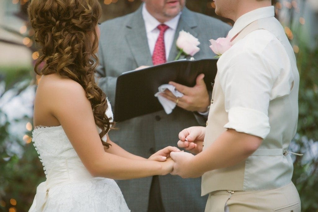 The bride and groom exchange rings during their wedding ceremony at Oak Tree Manor.