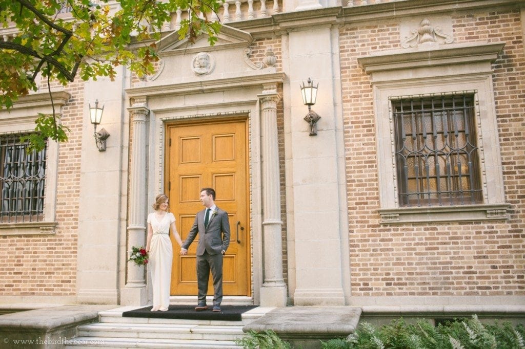The bride and groom hold hands on the steps in front of the Julia Ideson Library.