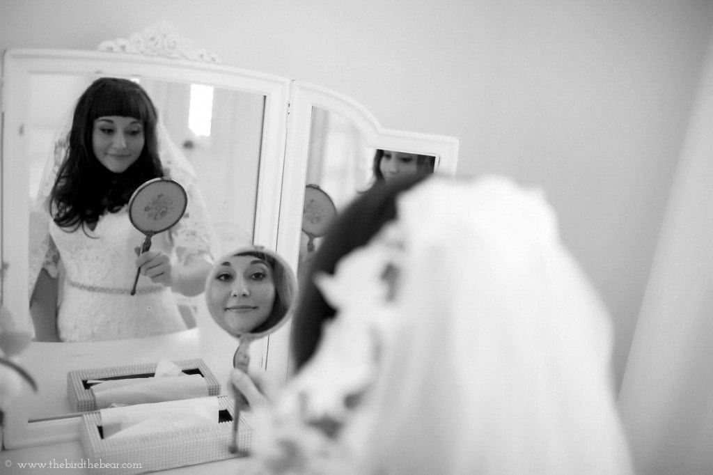 Bride looks in the mirror in Dove Cottage at the Heritage House in Dripping Springs, TX