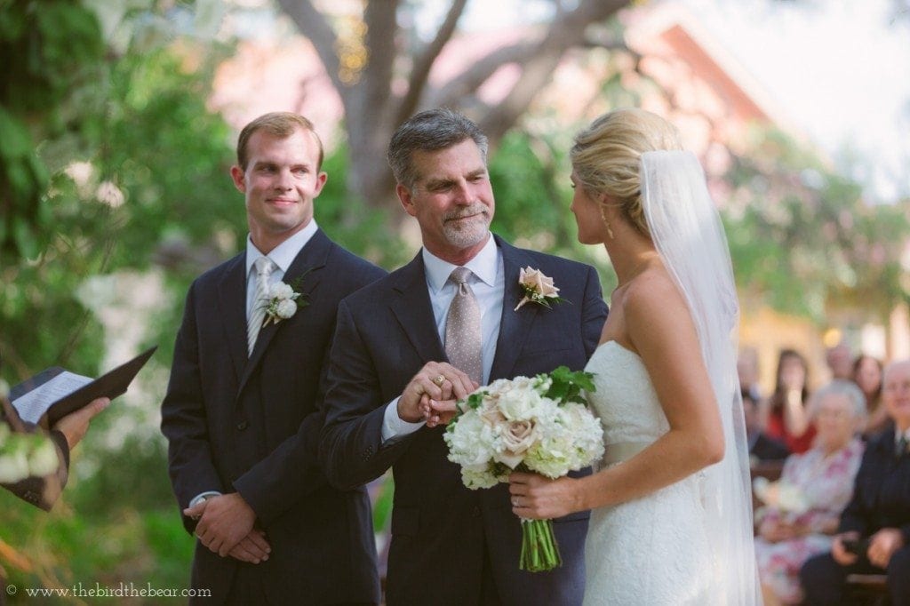 The bride's father hands her off to the groom at the front of the aisle at Sacred Oaks.