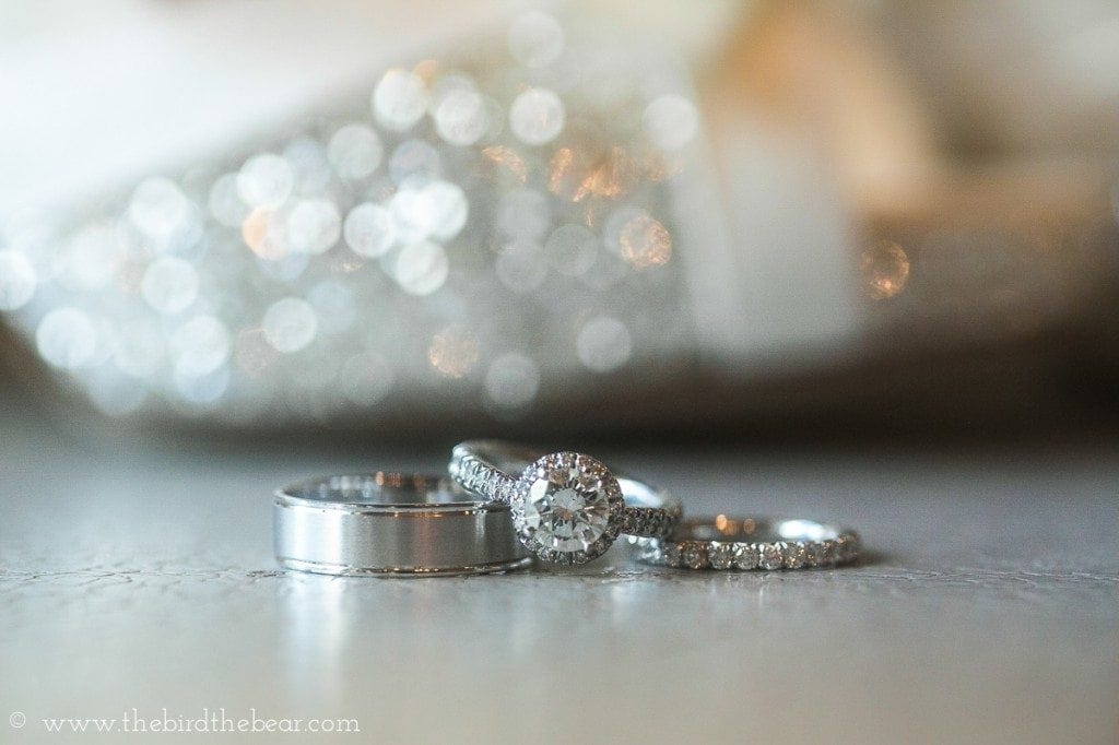 Diamond wedding ring sits in front of silver sparkley kate spade shoes.