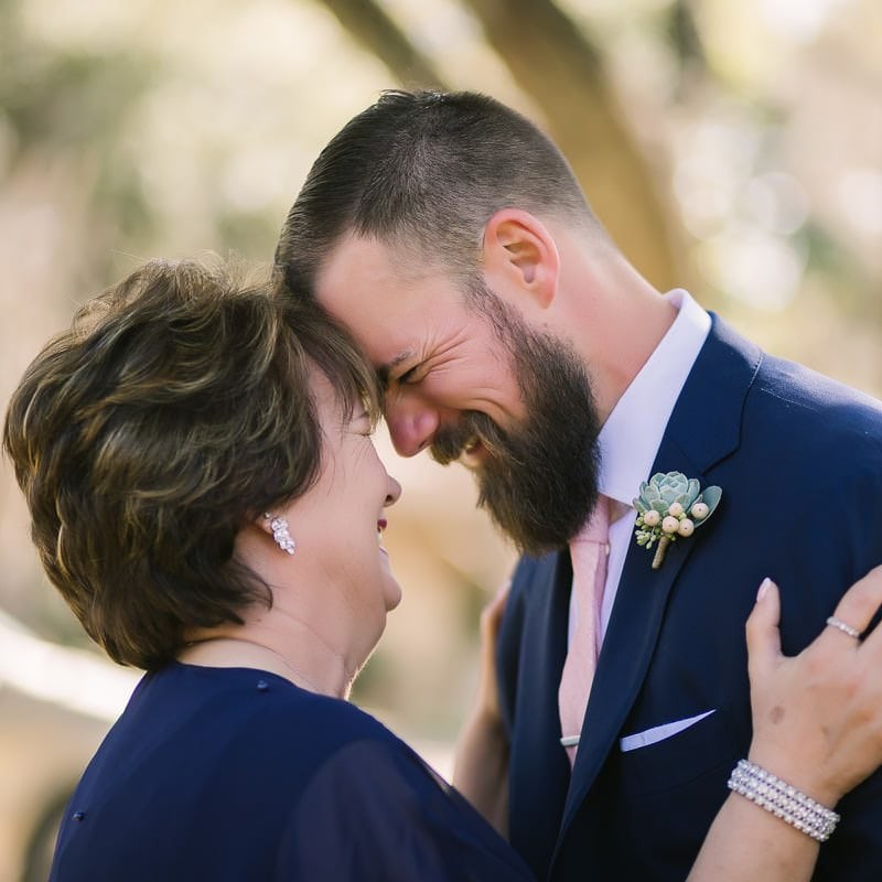 groom laughs with his mom as they embrace