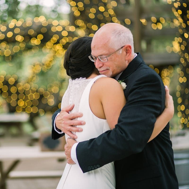 father of bride embraces his daughter at her wedding