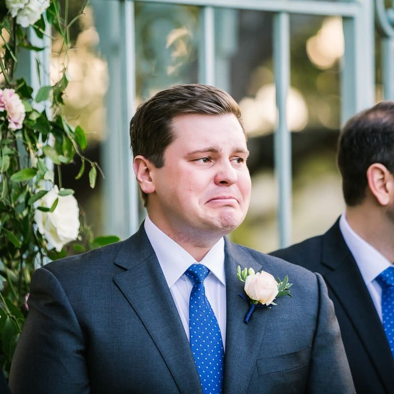 groom with tears in his eyes looks at his bride walking down the aisle