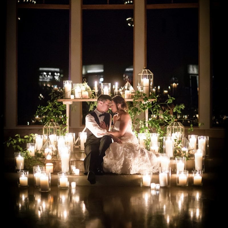 Bride and groom sit on steps of chapel at night and have romantic moment surrounded by candles