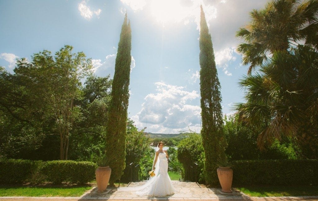 Bride stands in the garden at Laguna Gloria with a bright blue sky around her.