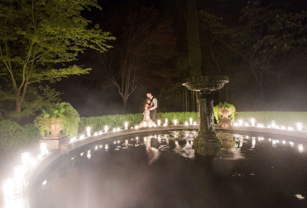 The bride and groom kiss during their evening reception by the fountain at the wedding venue Park Winters.