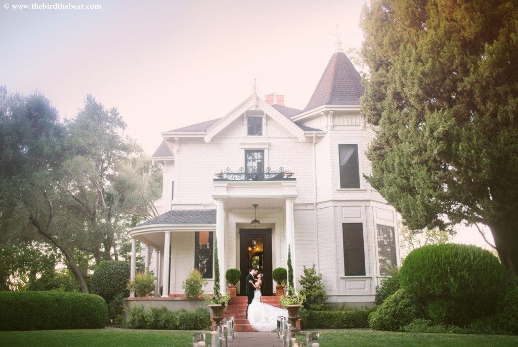 Bride and groom kiss in front of the victorian cottage at the Park Winters wedding venue in Northern California.