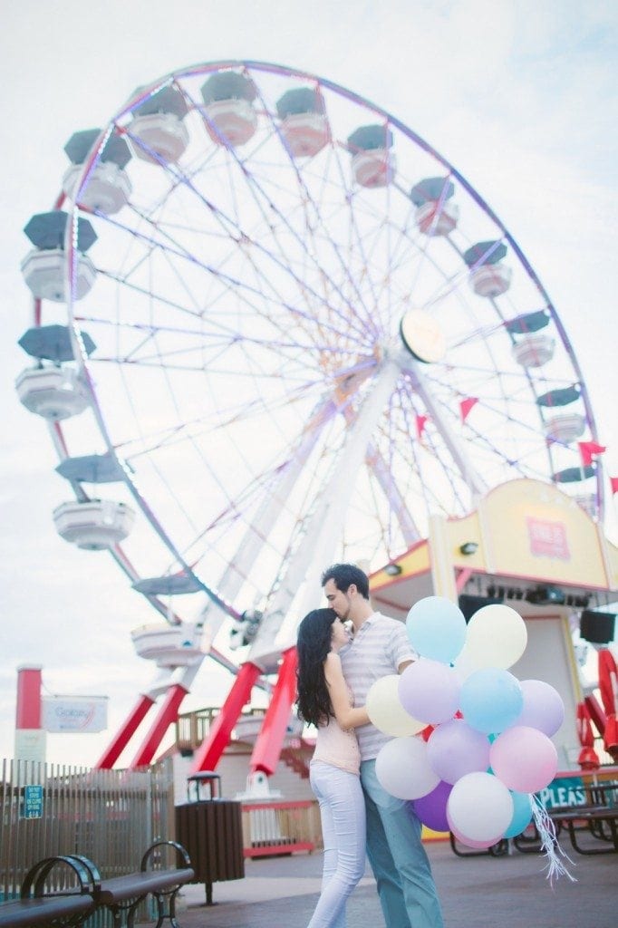 A bride and groom kiss in front of a ferris wheel at Pleasure Pier in Galveston, TX. 