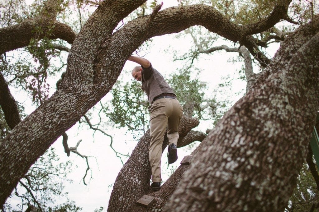 Groomsman climbs a tree at the ceremony site.