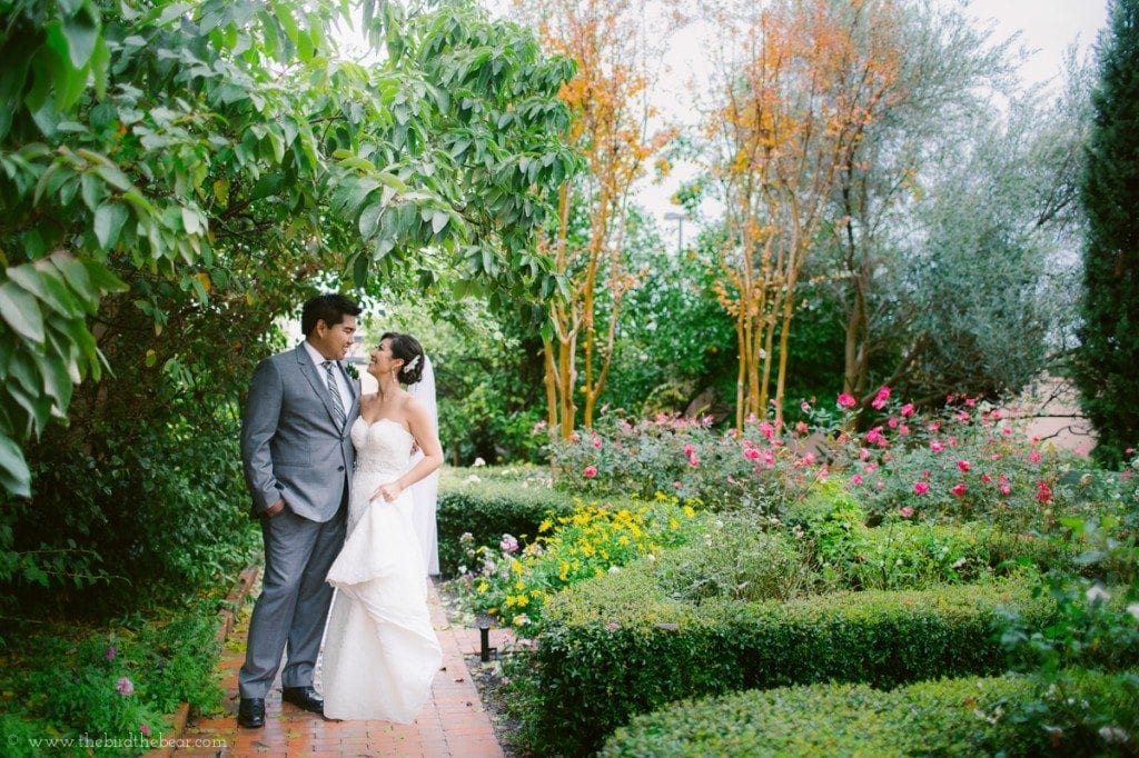 Bride and groom walk through the garden at the Parador in Houston, TX before their wedding ceremony.