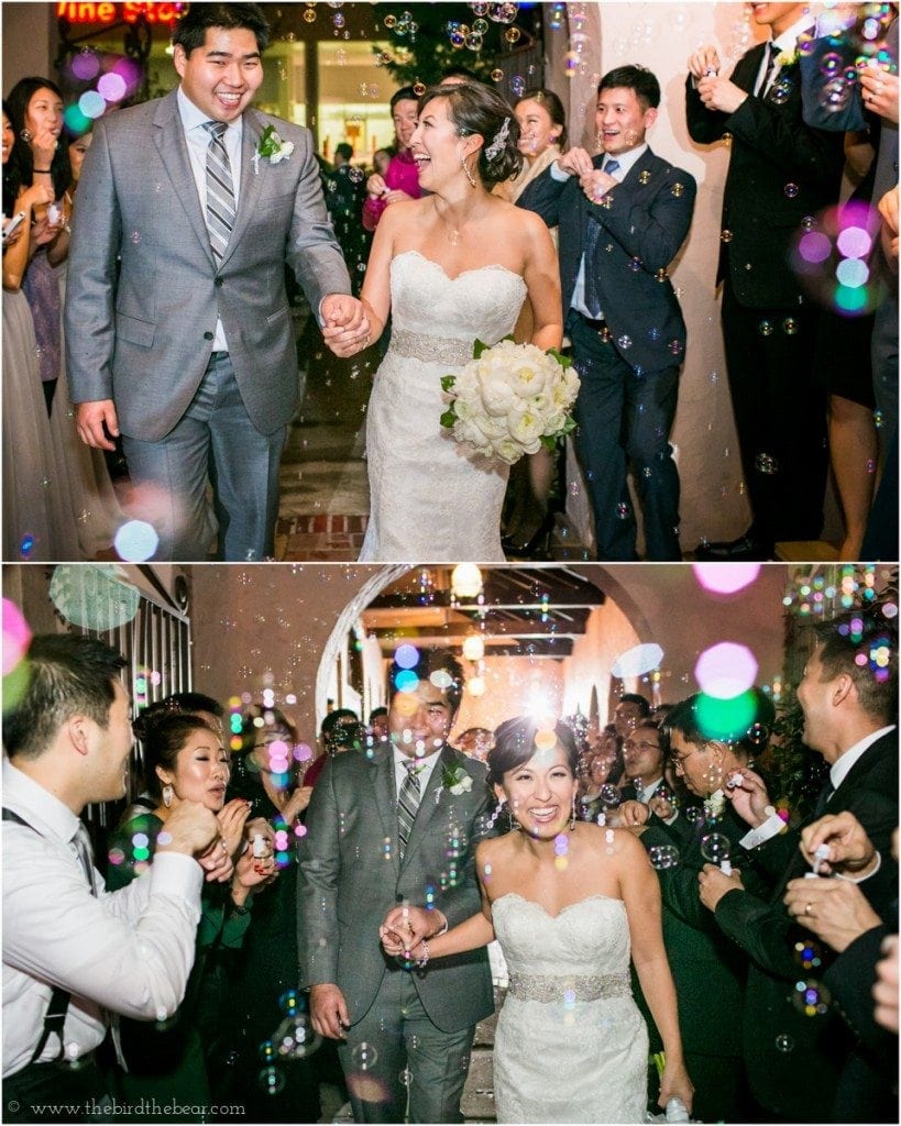 The bride and groom run through bubbles while exiting their wedding reception.
