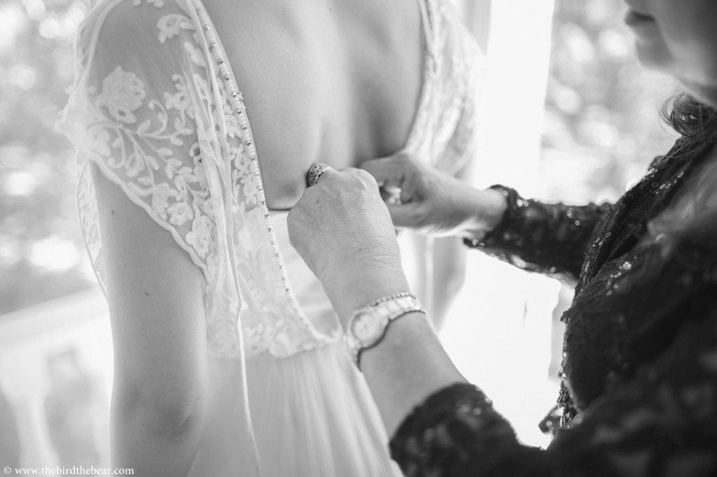 mother of the bride tying bride's gown