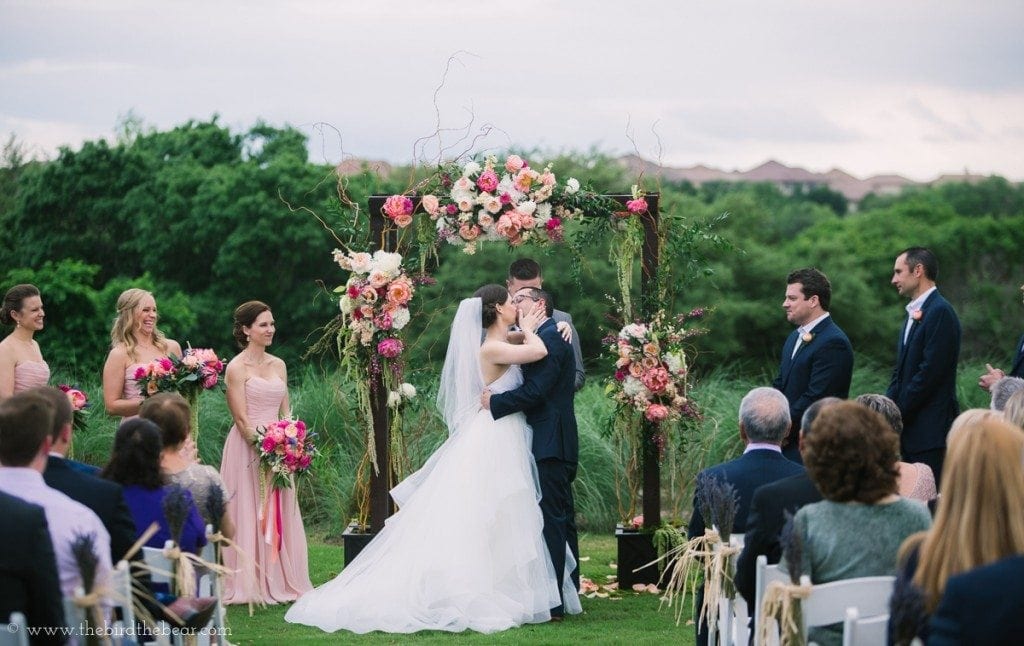 Bride and groom share their first kiss as man and wife at the University of Texas Golf Club in Austin.