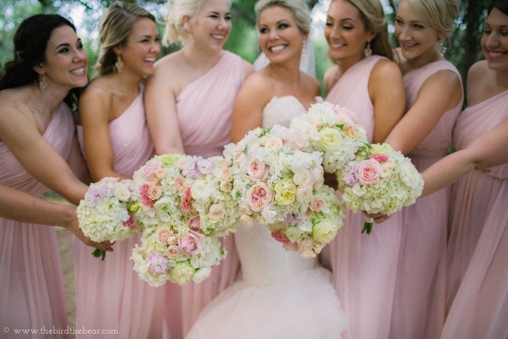 The bride and bridesmaids show off their pink and white wedding bouquets.