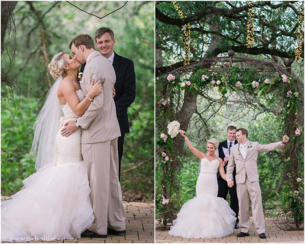 The bride and groom share their first kiss as man and wife under an alter of pink and white flowers.