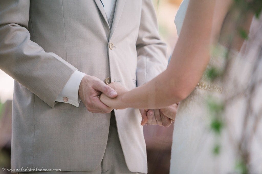 The bride and groom hold hands while saying their vows.