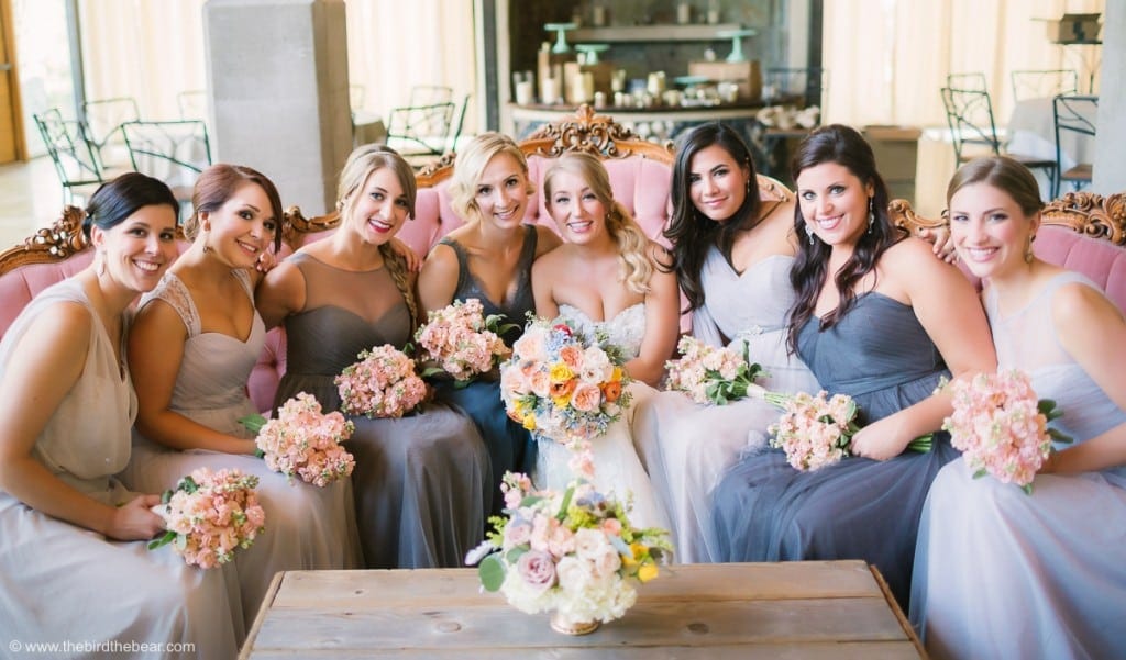 group photo of bridesmaids with bride on pink couch