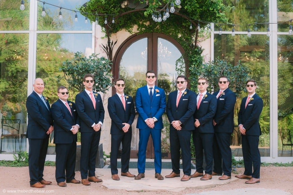 Groomsmen take sunglasses shot in front of reception hall