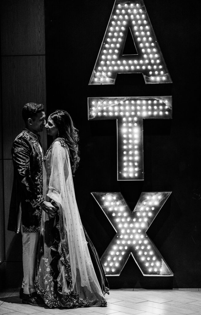 Bride and groom with ATX marquee letters at Maes Ridge wedding sangeet